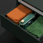Green cleaning tool with a gold cap in an open drawer with folded clothes