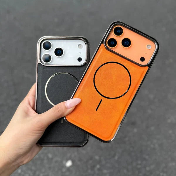 Hand holding two phone cases, one black and one orange with a circular design, on a dark surface.