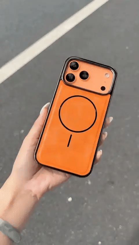 Hand holding an orange phone case with a black design on a gray surface