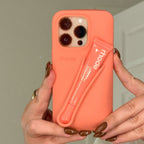 Coral phone case with a built-in lip balm held by hands against a neutral background