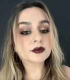 Close-up of a person with dark hair and makeup against a dark background