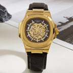 Gold watch with black leather strap on a white surface