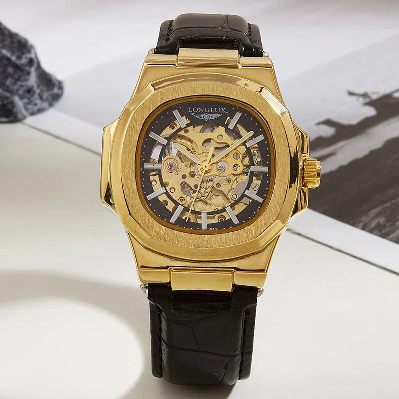 Gold watch with black leather strap on a white surface