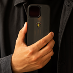 Person holding a black phone case with a logo, wearing a dark jacket and shirt.