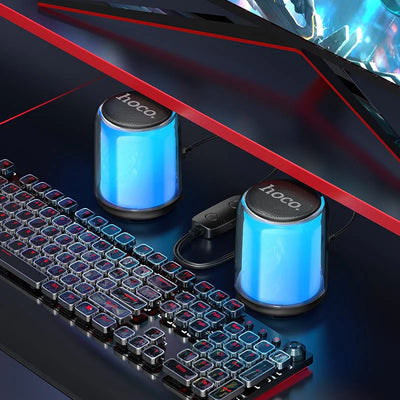 Blue Hoco speakers on a gaming desk setup with keyboard and monitor